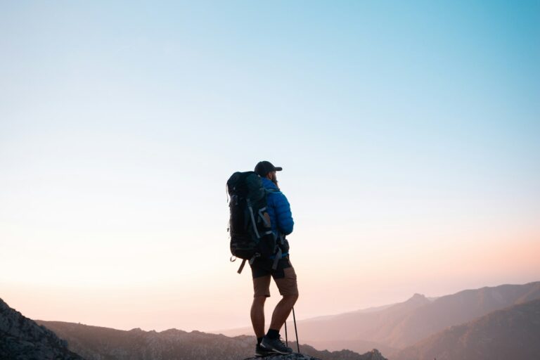 Hiker with a backpack on a rocky summit at sunrise